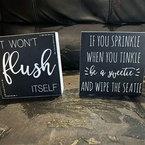 Two small wooden bathroom plaques.